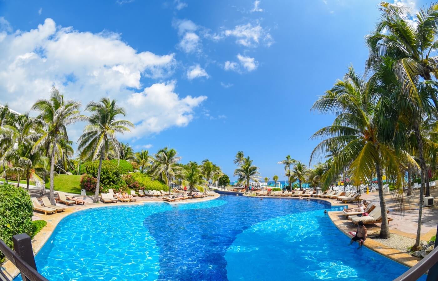 Albercas junto a un restaurante con palmeras en el Hotel Grand Oasis Cancun