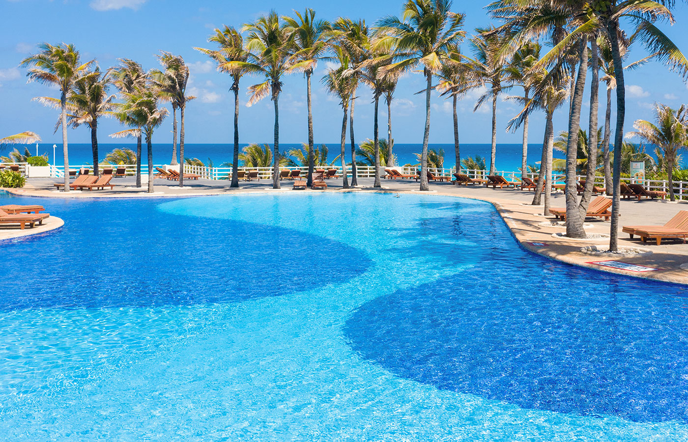 Swimming pools next to a palm tree restaurant at the Grand Oasis Cancun Hotel