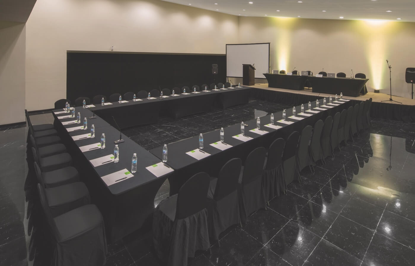Sala para reuniones con sillas, mesas y escenario en Oh! Cancun The Urban Oasis